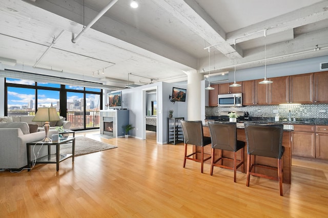 kitchen featuring stainless steel microwave, open floor plan, dark countertops, track lighting, and a kitchen breakfast bar