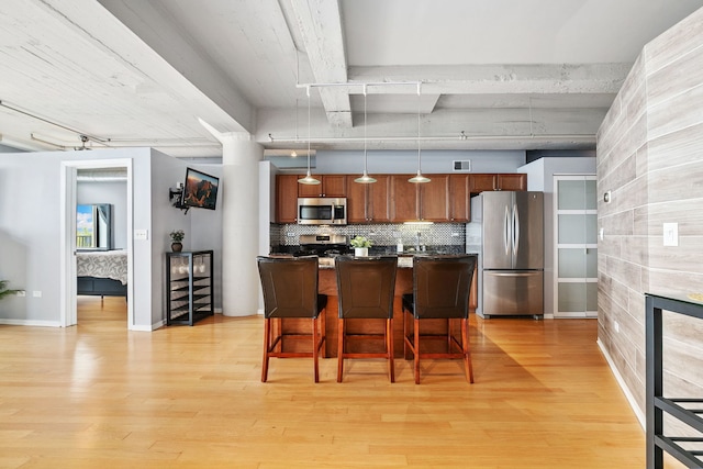 kitchen featuring stainless steel appliances, dark countertops, light wood-type flooring, and a breakfast bar area