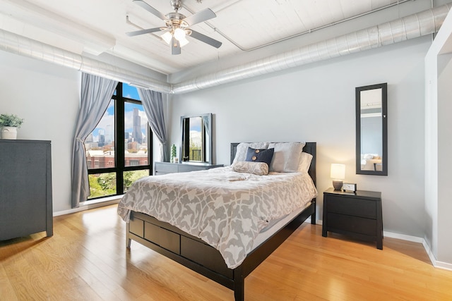 bedroom featuring wood finished floors, baseboards, and a view of city