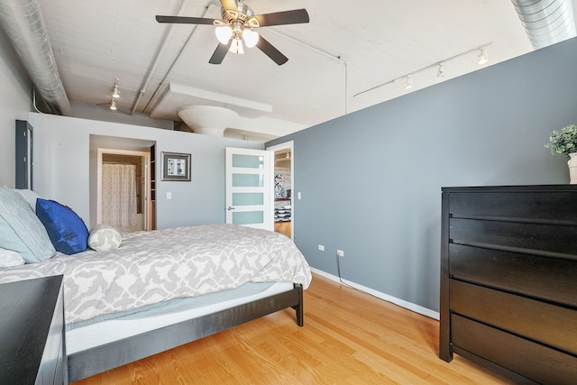 bedroom with track lighting, wood finished floors, baseboards, and a ceiling fan