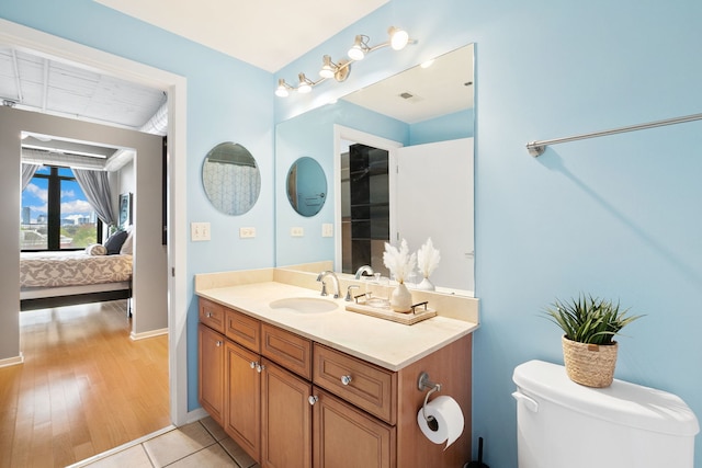 bathroom with ensuite bathroom, vanity, baseboards, toilet, and wood finished floors