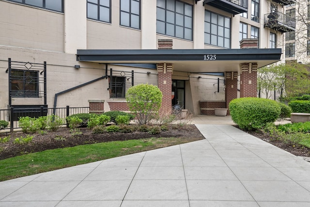 view of exterior entry featuring brick siding and fence