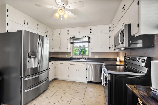 304 W Elm St, Fairbury, IL 61739 - kitchen with stainless steel appliances, a sink, light tile patterned floors, dark countertops, and ceiling fan
