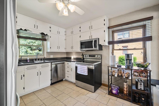 304 W Elm St, Fairbury, IL 61739 - kitchen with stainless steel appliances, a sink, dark countertops, light tile patterned floors, and white cabinets