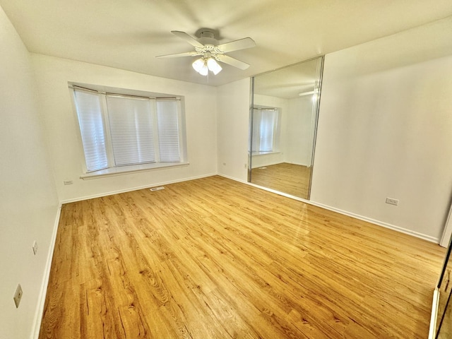 unfurnished bedroom with a ceiling fan, baseboards, light wood-type flooring, and a closet