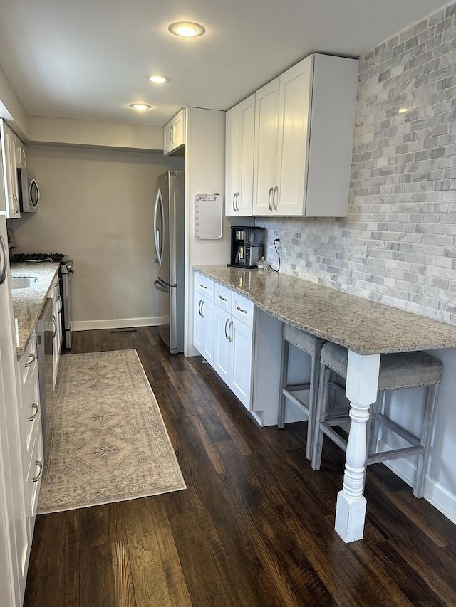 13319 S Mackinaw Ave, Chicago, IL 60633 - kitchen featuring stainless steel appliances, white cabinets, backsplash, light stone counters, and dark wood-style floors