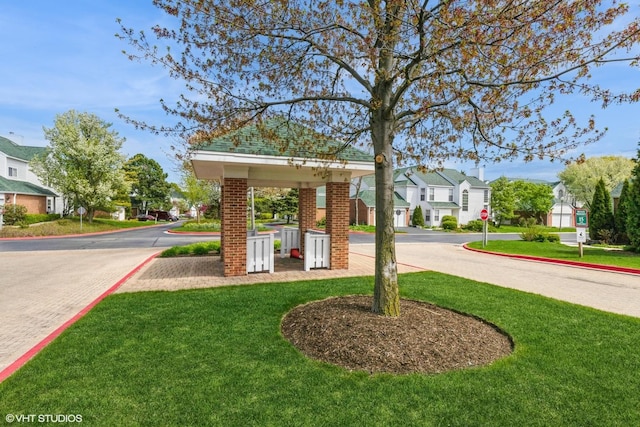 view of property's community featuring a lawn, a residential view, and curved driveway