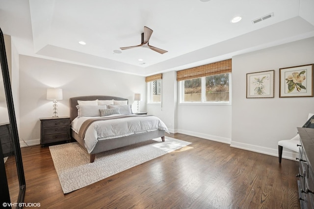 bedroom featuring a raised ceiling, baseboards, dark wood-style flooring, recessed lighting, and a ceiling fan
