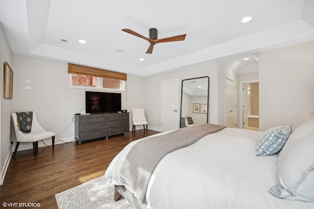 bedroom with dark wood-style floors, a tray ceiling, recessed lighting, and baseboards