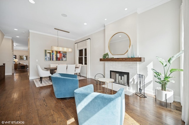 living area with wood finished floors, a brick fireplace, ornamental molding, recessed lighting, and baseboards