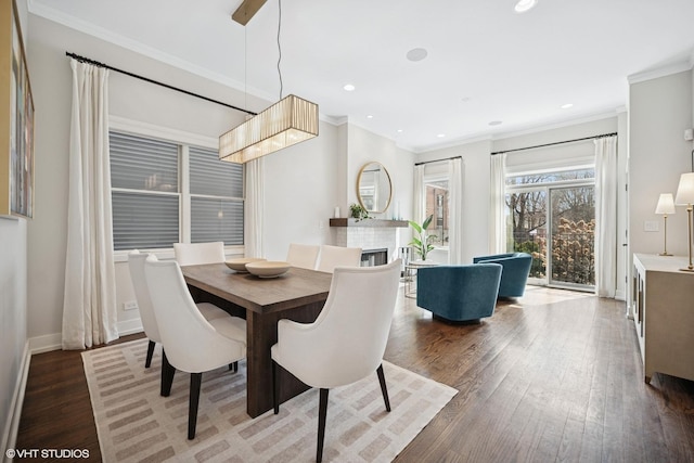 dining area with wood finished floors, ornamental molding, baseboards, recessed lighting, and a fireplace