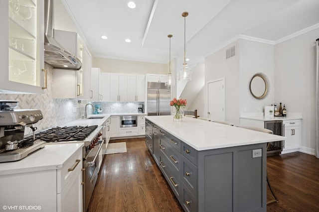kitchen featuring high end appliances, gray cabinetry, wall chimney range hood, beverage cooler, and a kitchen island