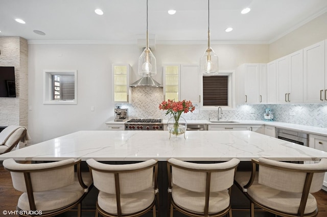 kitchen featuring tasteful backsplash, light stone counters, a kitchen island, wall chimney range hood, and recessed lighting
