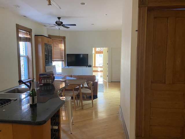 interior space with brown cabinetry, light wood-type flooring, recessed lighting, ceiling fan, and dark countertops