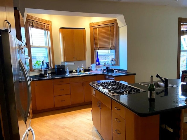 kitchen featuring dark countertops, stainless steel appliances, a sink, and light wood-style floors