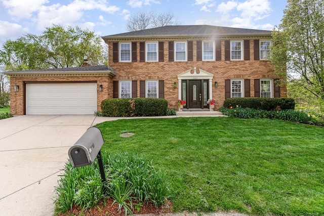colonial-style house featuring a garage, a front lawn, brick siding, and driveway