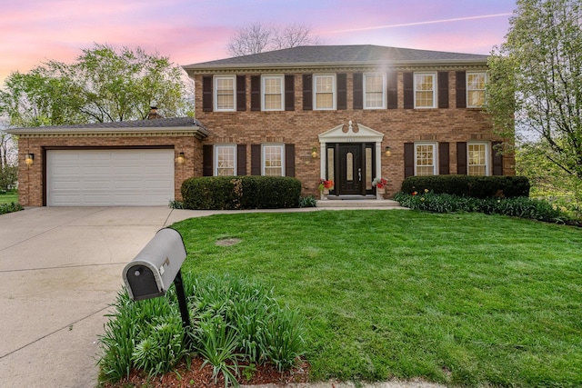 colonial home featuring concrete driveway, an attached garage, brick siding, and a front yard