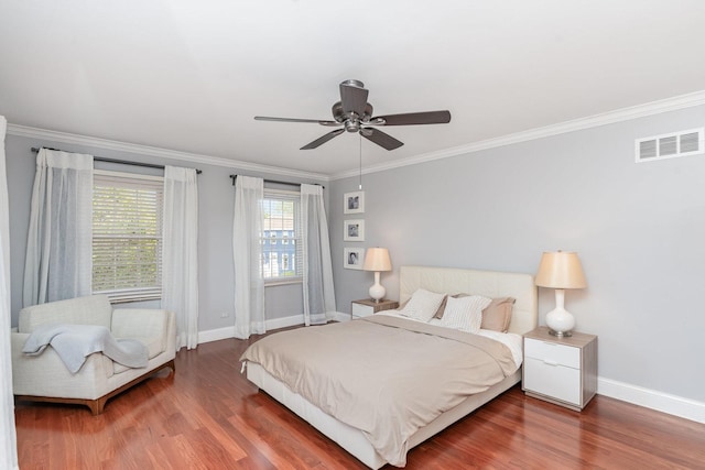 bedroom featuring wood finished floors, visible vents, baseboards, and ornamental molding