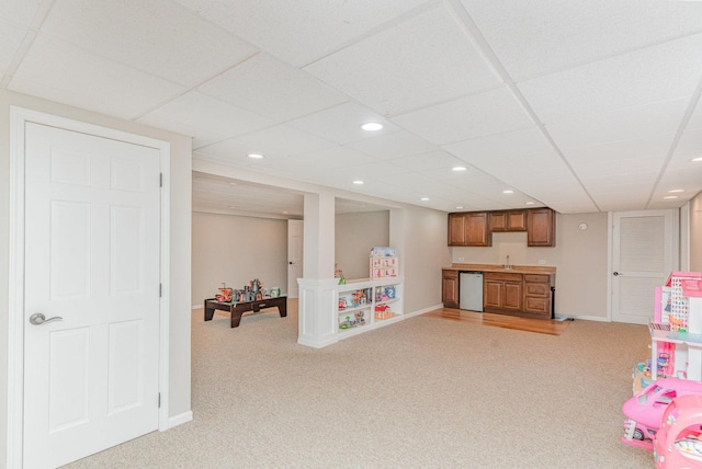rec room with wet bar, a drop ceiling, a sink, and light colored carpet