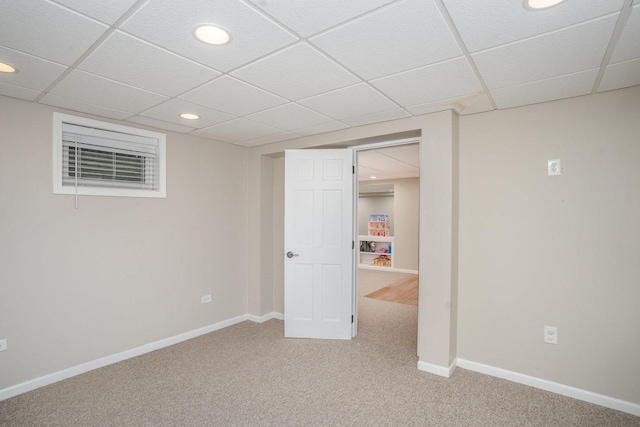 finished basement featuring a paneled ceiling, light colored carpet, recessed lighting, and baseboards