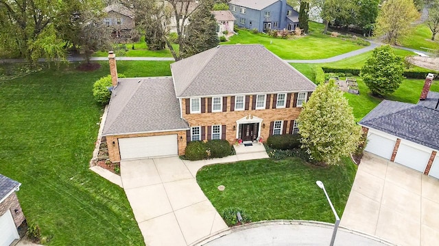 colonial inspired home with an attached garage, brick siding, driveway, and a front lawn