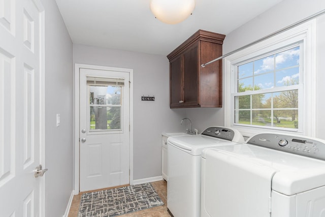 washroom with a sink, cabinet space, baseboards, and independent washer and dryer