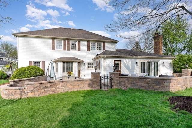 rear view of house featuring a chimney, a patio area, a lawn, and a gate