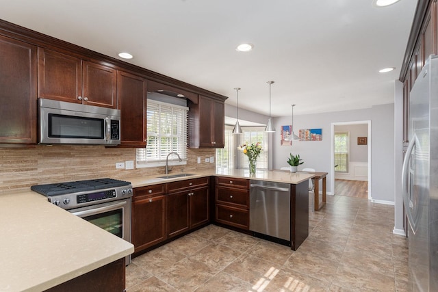 kitchen with a sink, a peninsula, stainless steel appliances, and light countertops