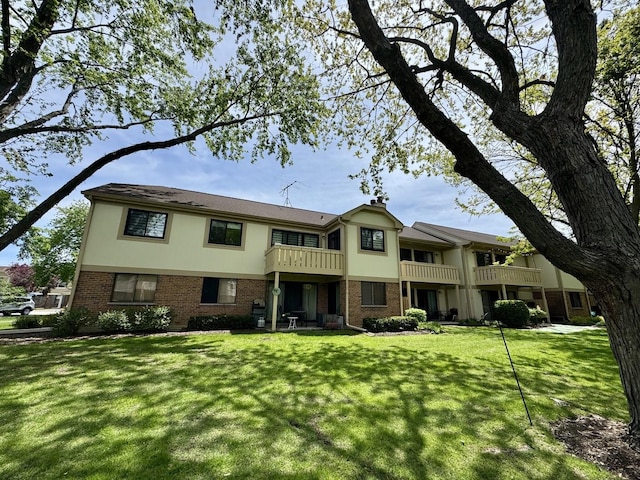 584 Williamsburg Ct Unit C2, Wheeling, IL 60090 - view of front of property featuring a balcony, brick siding, a front yard, and stucco siding