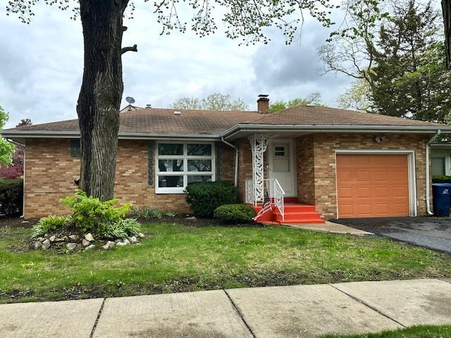2010 W Monroe St, Waukegan, IL 60085 - ranch-style house featuring an attached garage, brick siding, a chimney, and asphalt driveway