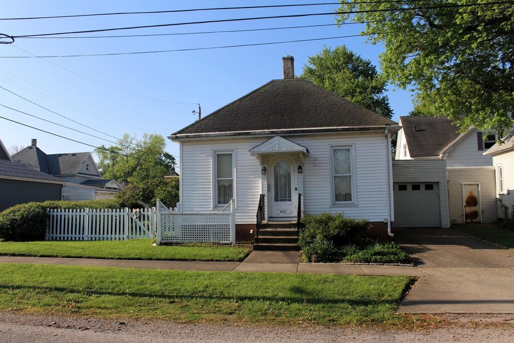 416 W Macon St, Clinton, IL 61727 - view of front of house with a garage, a chimney, fence, concrete driveway, and a shingled roof