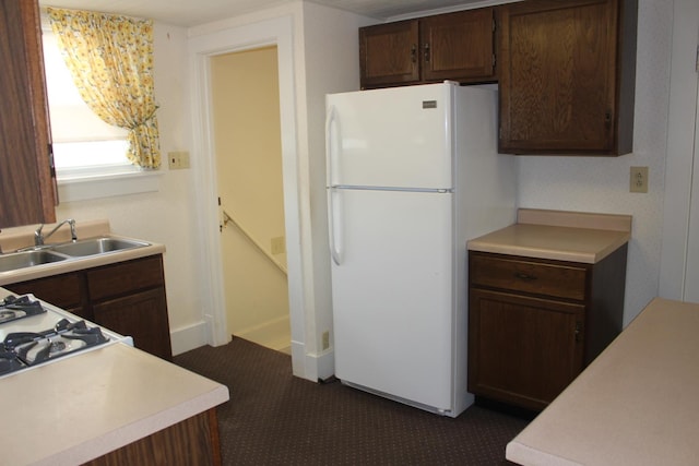 kitchen with freestanding refrigerator, light countertops, dark colored carpet, and a sink