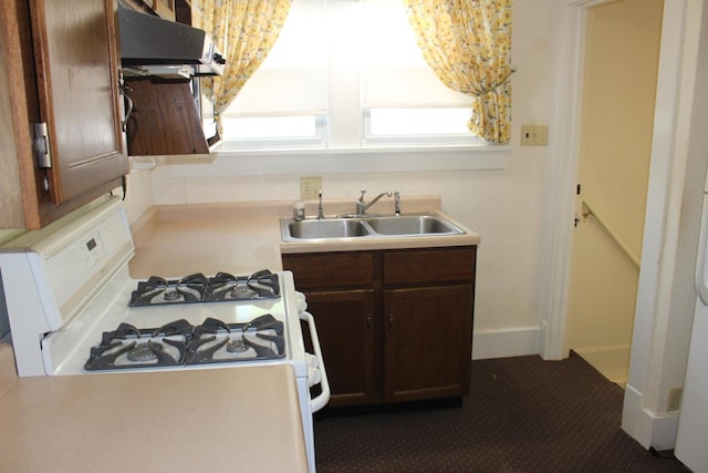 kitchen with under cabinet range hood, dark brown cabinets, a sink, light countertops, and white range with gas cooktop