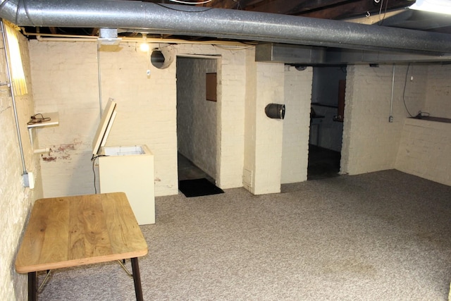 unfinished below grade area featuring brick wall and carpet floors