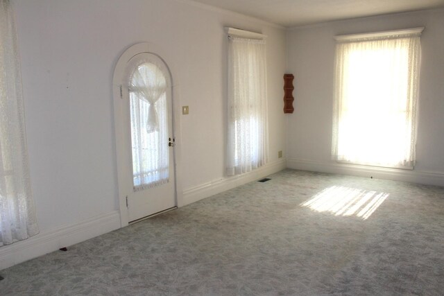 foyer with arched walkways, carpet flooring, and crown molding