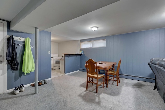 dining area with a baseboard radiator, wooden walls, and light colored carpet