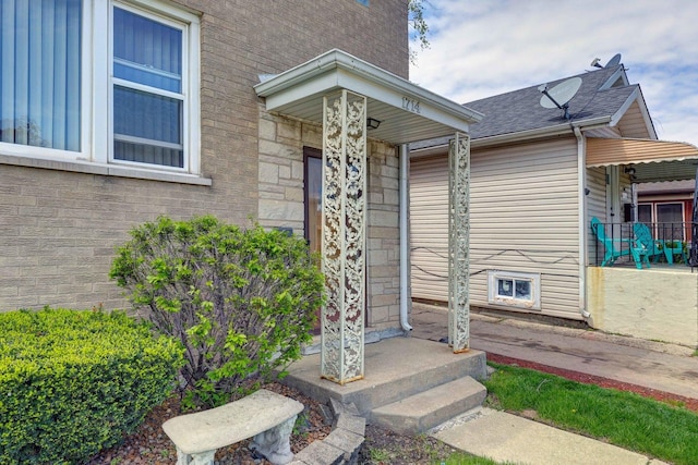 view of exterior entry featuring a shingled roof