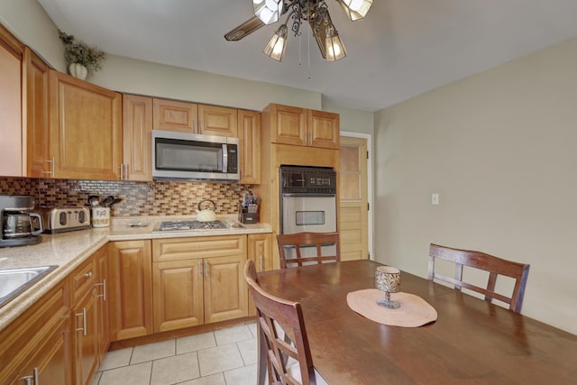 kitchen featuring stainless steel appliances, ceiling fan, backsplash, light tile patterned floors, and light countertops