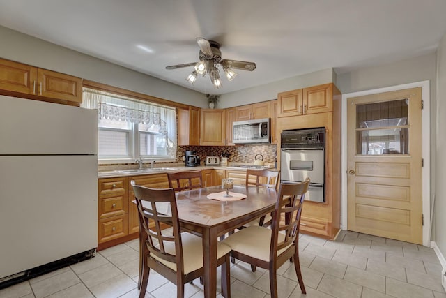 dining space featuring a ceiling fan, light tile patterned floors, and baseboards