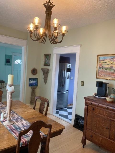 dining area with an inviting chandelier, a textured ceiling, and light wood-style floors