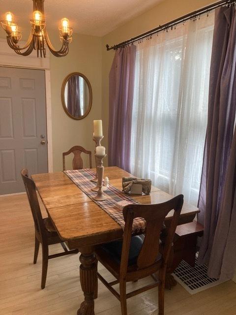 dining area with light wood-style floors and an inviting chandelier