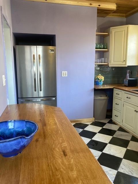 kitchen featuring freestanding refrigerator, open shelves, tile patterned floors, backsplash, and white cabinets