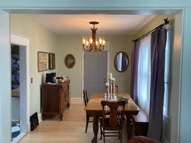 dining area featuring light wood-style flooring and a notable chandelier