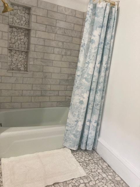full bath featuring baseboards and shower / bath combination with curtain