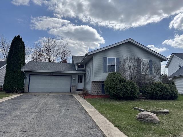 tri-level home featuring aphalt driveway, an attached garage, brick siding, and a front yard