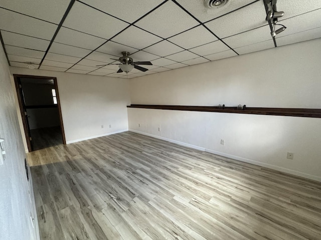 unfurnished room with a paneled ceiling, baseboards, and wood finished floors