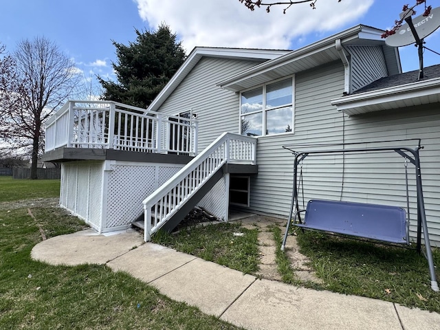 rear view of house with a deck, a lawn, and stairs