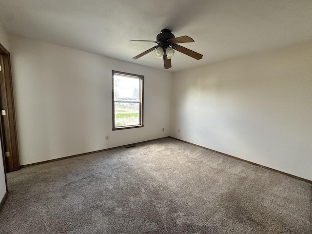 empty room with carpet floors, a ceiling fan, and baseboards
