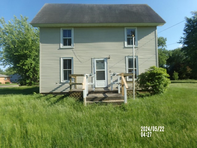 back of property with a deck and a lawn