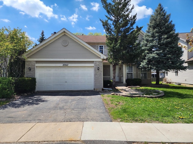 view of front of home with asphalt driveway, a front lawn, a garage, and brick siding